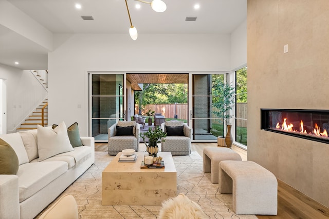 living area featuring light wood-style floors, stairway, a healthy amount of sunlight, and visible vents