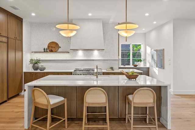 kitchen with light wood-style floors, custom range hood, backsplash, visible vents, and recessed lighting