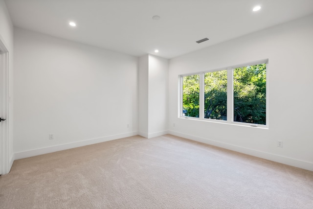 empty room featuring light colored carpet, baseboards, visible vents, and recessed lighting