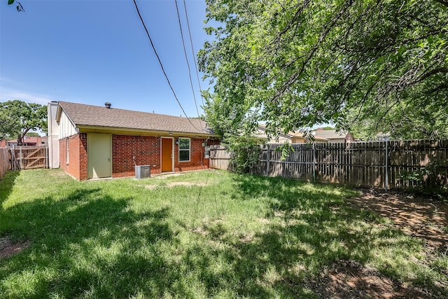 rear view of house with a fenced backyard, brick siding, and a lawn