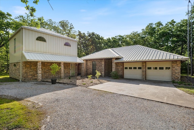 view of front facade featuring concrete driveway, a garage, stone siding, and metal roof