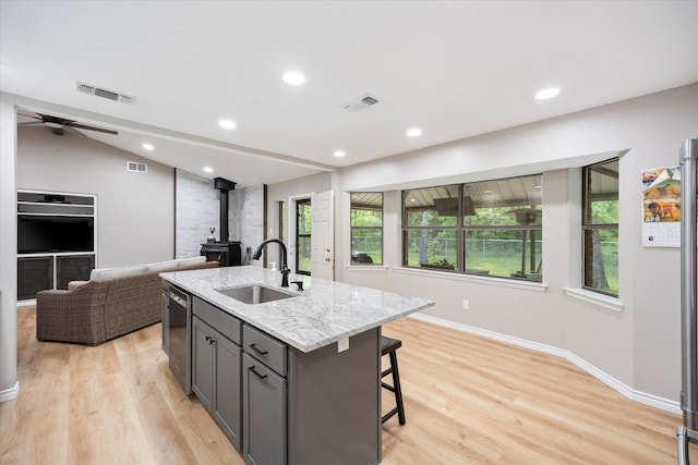 kitchen featuring gray cabinets, a wood stove, a sink, and visible vents