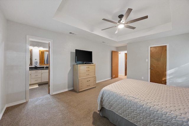 bedroom featuring a raised ceiling, visible vents, baseboards, light colored carpet, and ceiling fan