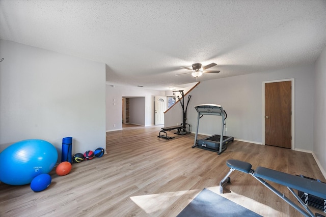 exercise area with baseboards, a ceiling fan, wood finished floors, and a textured ceiling