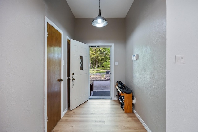 entryway with baseboards, a textured wall, and light wood finished floors