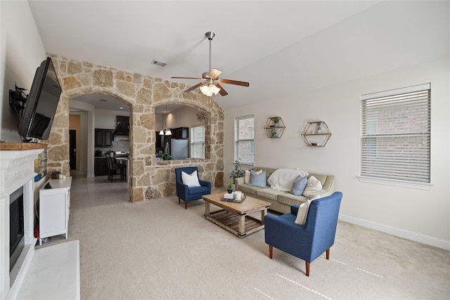 living room with a fireplace, arched walkways, a wealth of natural light, and ceiling fan