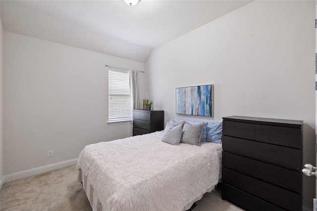 bedroom featuring lofted ceiling, baseboards, and light colored carpet