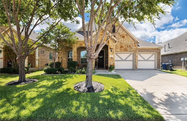 view of front of house featuring a front lawn, concrete driveway, stone siding, roof with shingles, and a garage