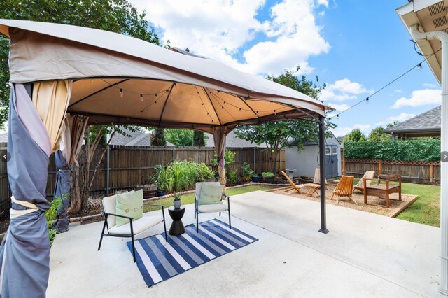 view of patio / terrace featuring a fenced backyard, an outdoor structure, a gazebo, and a storage shed