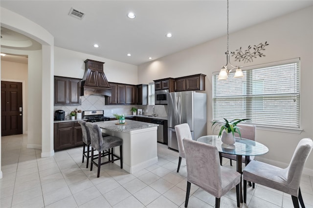 kitchen featuring a center island, dark brown cabinets, a sink, appliances with stainless steel finishes, and visible vents