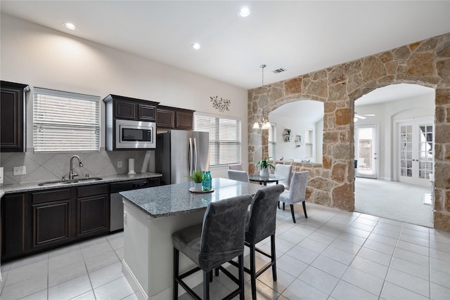 kitchen with light tile patterned flooring, a breakfast bar area, stainless steel appliances, and a sink