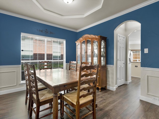 1803 Timber Ridge Dr, Frisco, TX 75036 - dining area featuring arched walkways, plenty of natural light, a wainscoted wall, a raised ceiling, and dark wood-type flooring