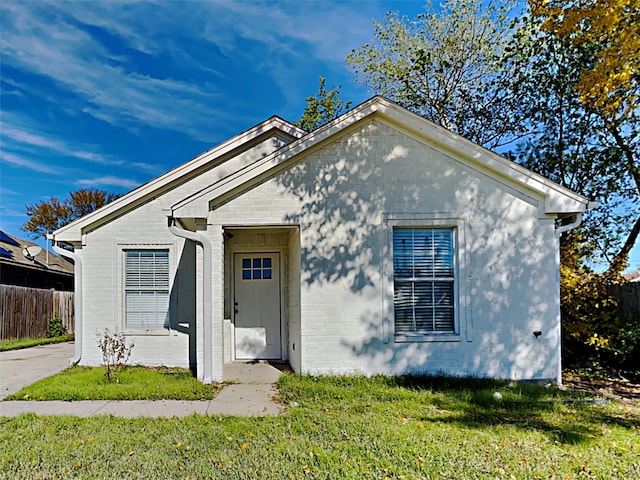 bungalow-style home featuring brick siding, a front yard, and fence
