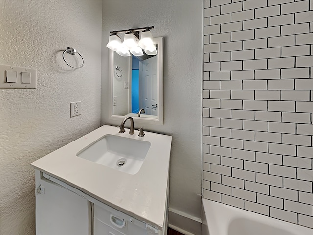 bathroom with a textured wall, vanity, and shower / bath combination