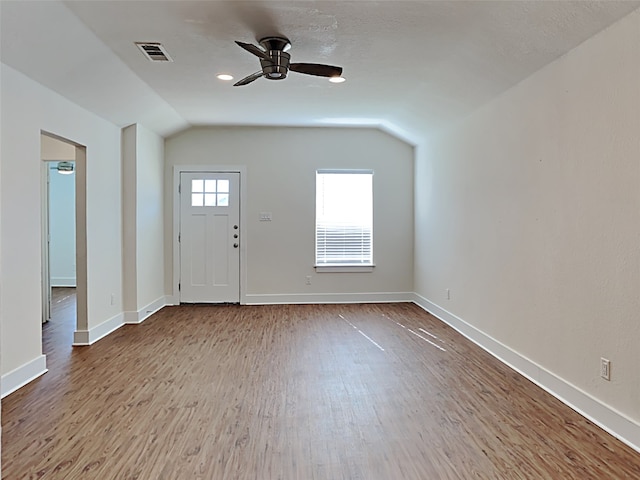entrance foyer with lofted ceiling, wood finished floors, visible vents, a ceiling fan, and baseboards