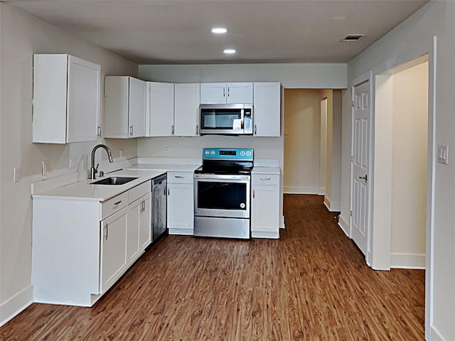 kitchen with stainless steel appliances, a sink, visible vents, wood finished floors, and light countertops