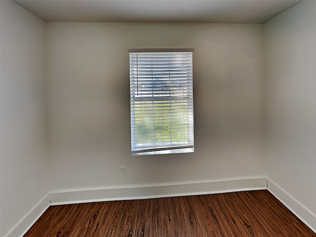 spare room featuring baseboards and dark wood-style flooring