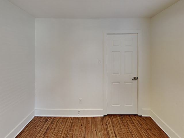 empty room featuring dark wood finished floors and baseboards