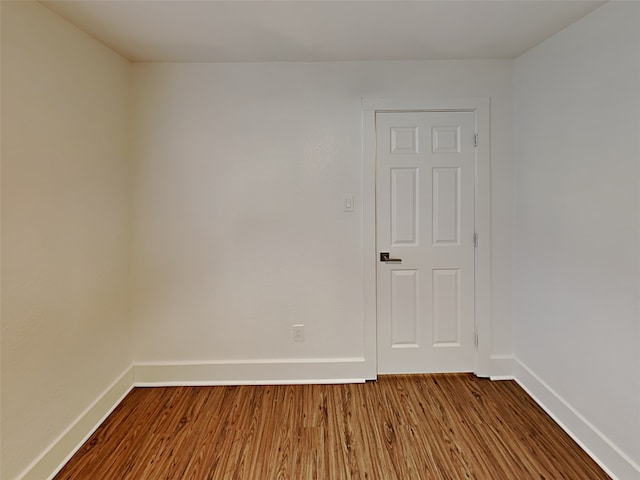 spare room with baseboards and dark wood-style flooring