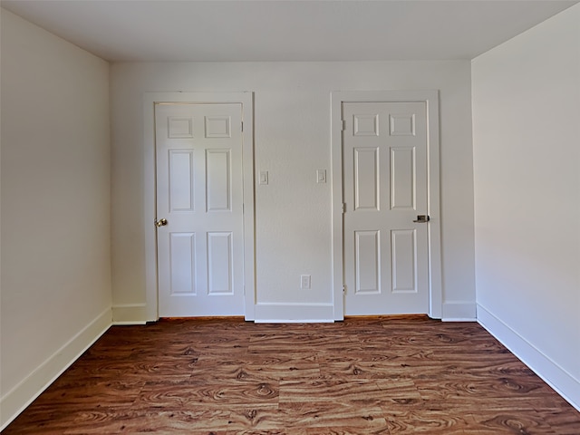 unfurnished bedroom with baseboards and dark wood-style flooring
