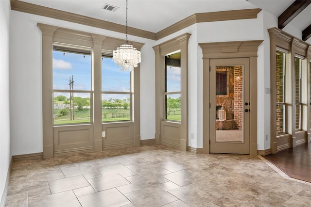 entryway featuring crown molding, a notable chandelier, baseboards, and visible vents