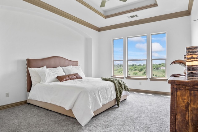 carpeted bedroom with baseboards, a raised ceiling, ornamental molding, and visible vents