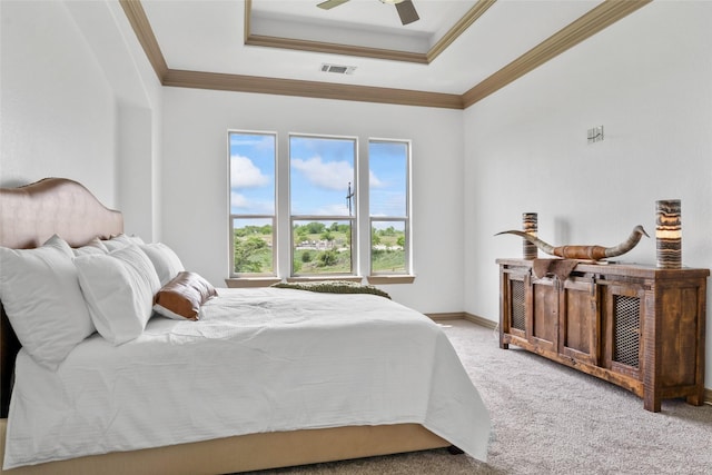 carpeted bedroom with a tray ceiling, ornamental molding, a ceiling fan, and visible vents