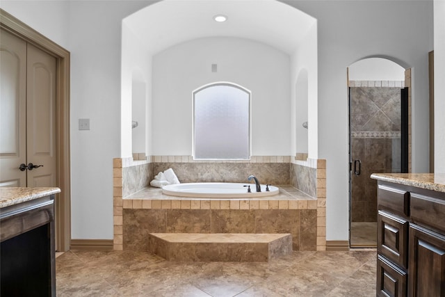 full bath featuring a stall shower, vanity, and a garden tub