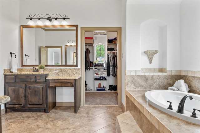 bathroom featuring tile patterned flooring, a garden tub, vanity, and a walk in closet