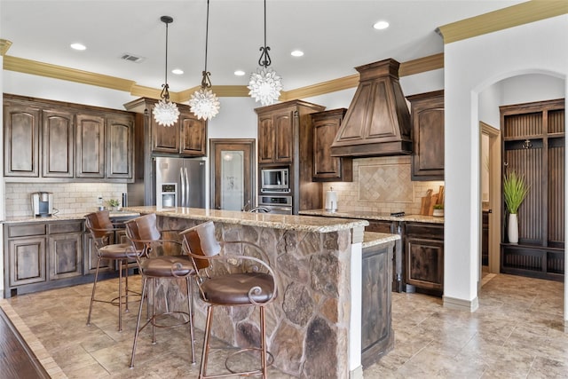 kitchen featuring stainless steel appliances, visible vents, custom range hood, and backsplash