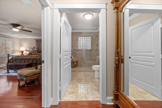 full bath with crown molding, a stall shower, a ceiling fan, toilet, and wood finished floors