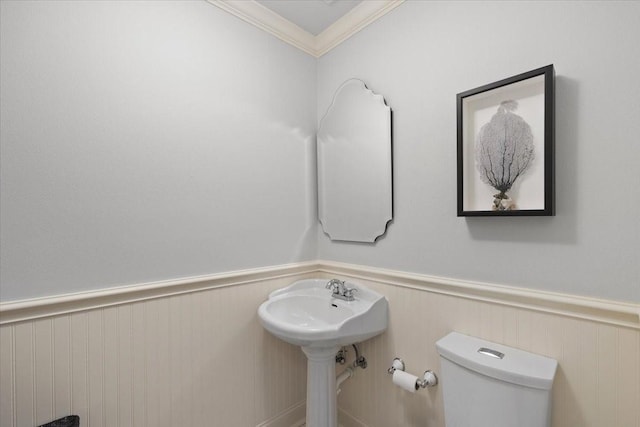 bathroom with a wainscoted wall, toilet, and ornamental molding