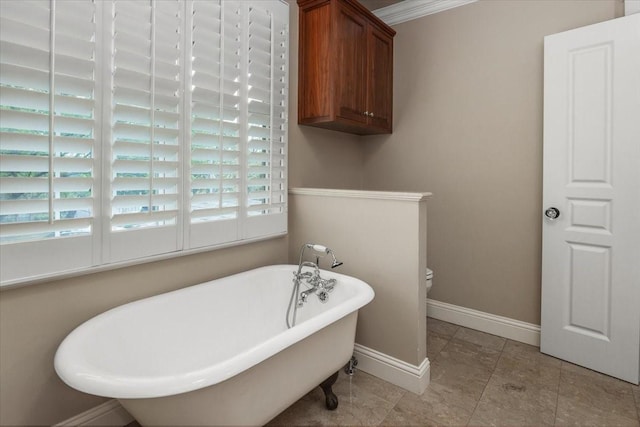 bathroom with a freestanding tub, toilet, baseboards, and tile patterned floors