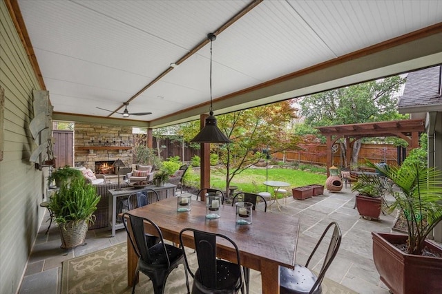 view of patio with a fenced backyard, ceiling fan, outdoor dining space, and an outdoor living space with a fireplace