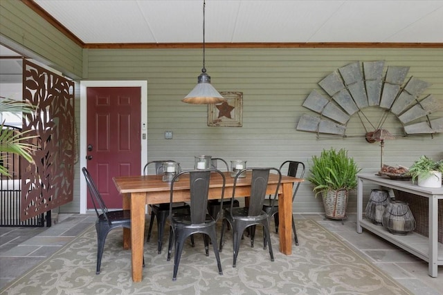 dining space with stone tile flooring and wooden walls