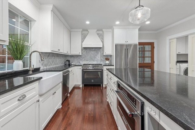 kitchen featuring high end appliances, washer / clothes dryer, premium range hood, a sink, and backsplash