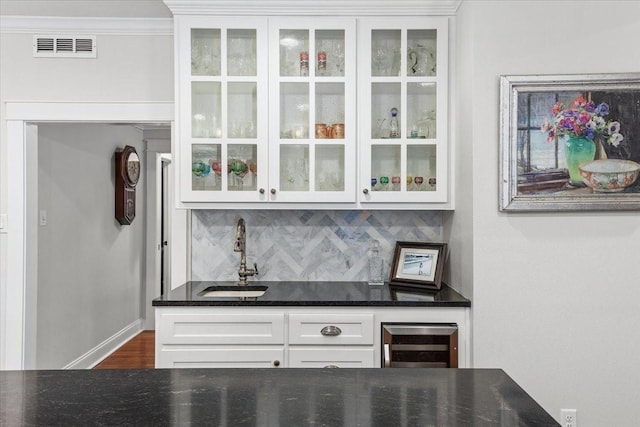 indoor wet bar with wine cooler, tasteful backsplash, and baseboards