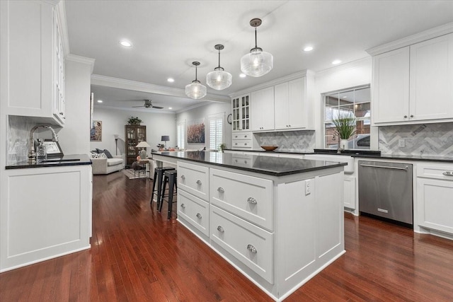 kitchen featuring stainless steel dishwasher, dark countertops, ornamental molding, a sink, and a ceiling fan