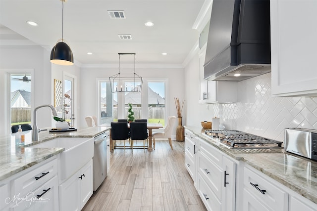 kitchen featuring crown molding, custom exhaust hood, a sink, appliances with stainless steel finishes, and visible vents