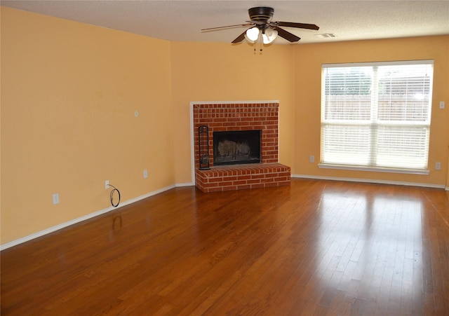 unfurnished living room featuring visible vents, baseboards, a ceiling fan, wood finished floors, and a fireplace