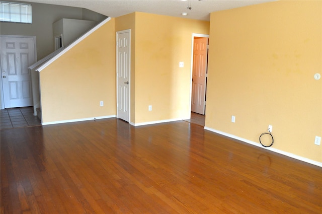unfurnished living room featuring ceiling fan, baseboards, wood finished floors, and stairs