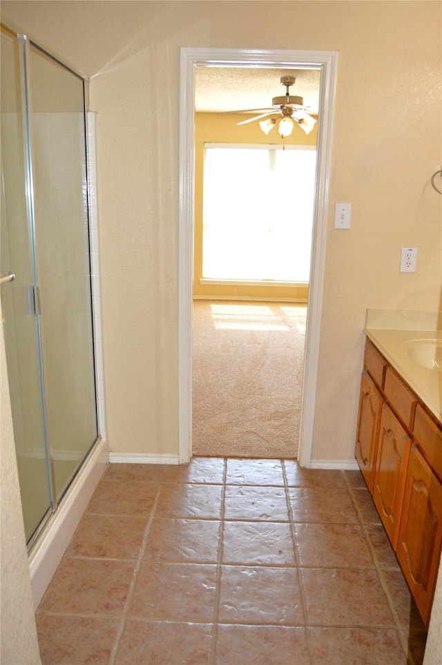bathroom featuring baseboards, vanity, a shower stall, and ceiling fan