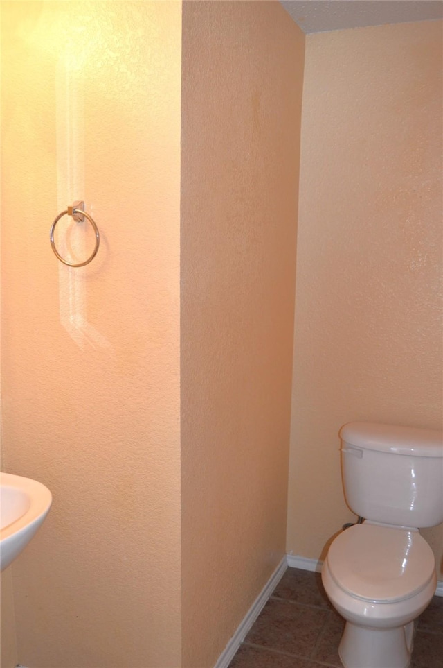 bathroom featuring toilet, tile patterned flooring, and baseboards