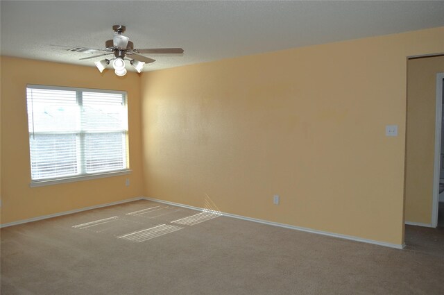 carpeted empty room featuring visible vents, baseboards, and ceiling fan