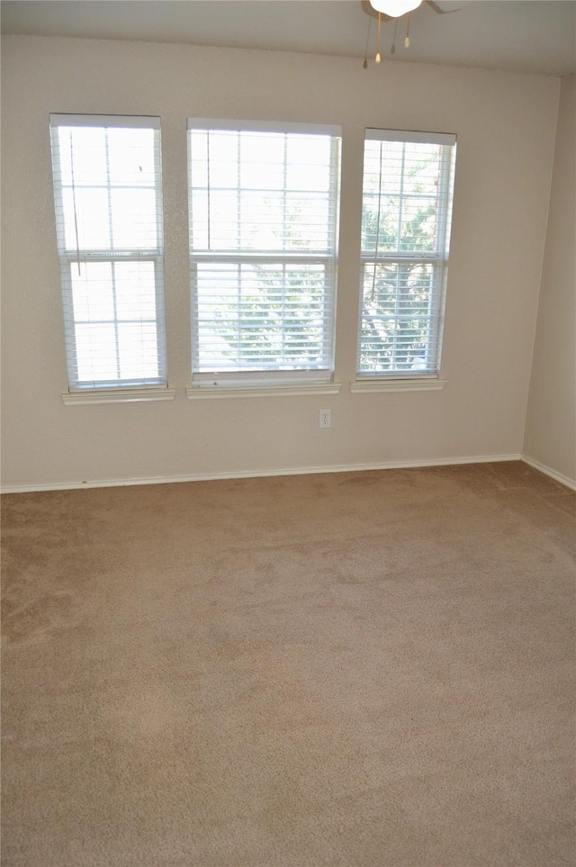 carpeted empty room featuring a ceiling fan and baseboards