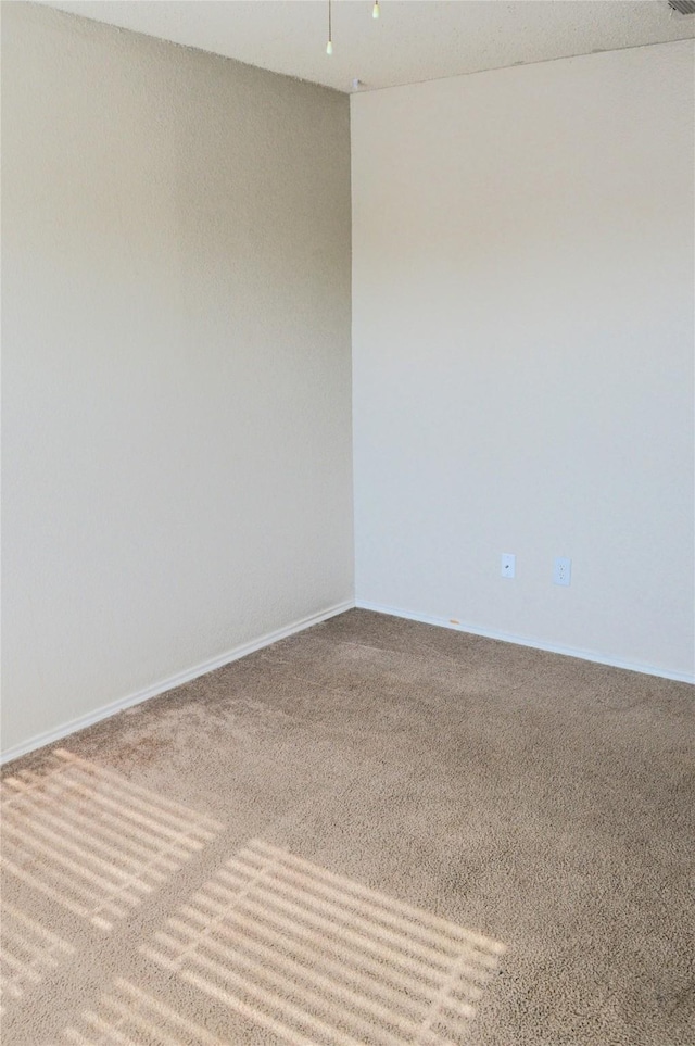 spare room featuring carpet floors and baseboards