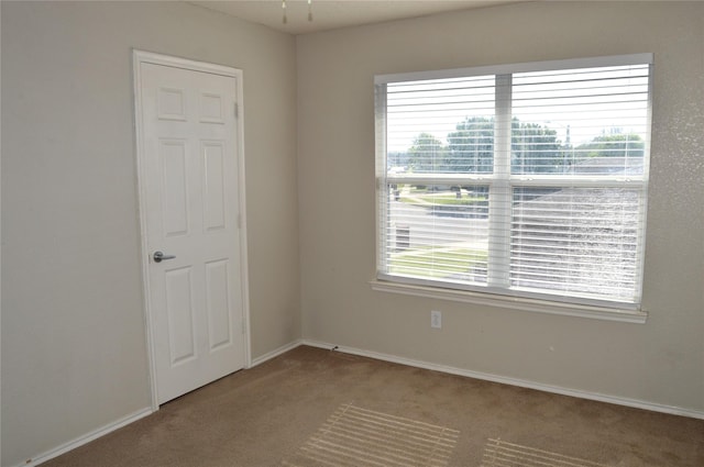 spare room featuring carpet flooring and baseboards