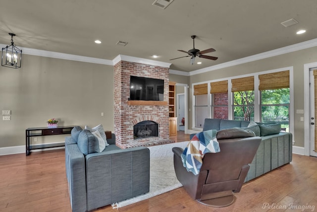 living area featuring ornamental molding, wood finished floors, visible vents, and ceiling fan with notable chandelier