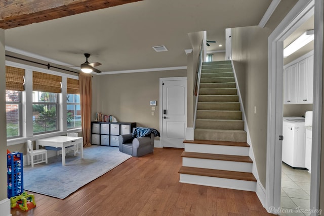 stairway featuring visible vents, separate washer and dryer, wood finished floors, ceiling fan, and ornamental molding