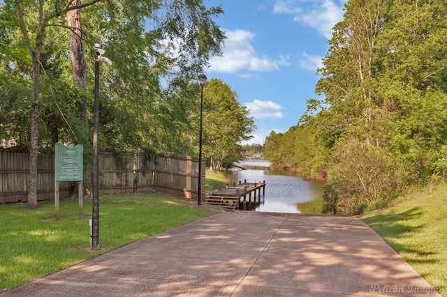 view of home's community featuring a yard, a boat dock, a water view, and fence